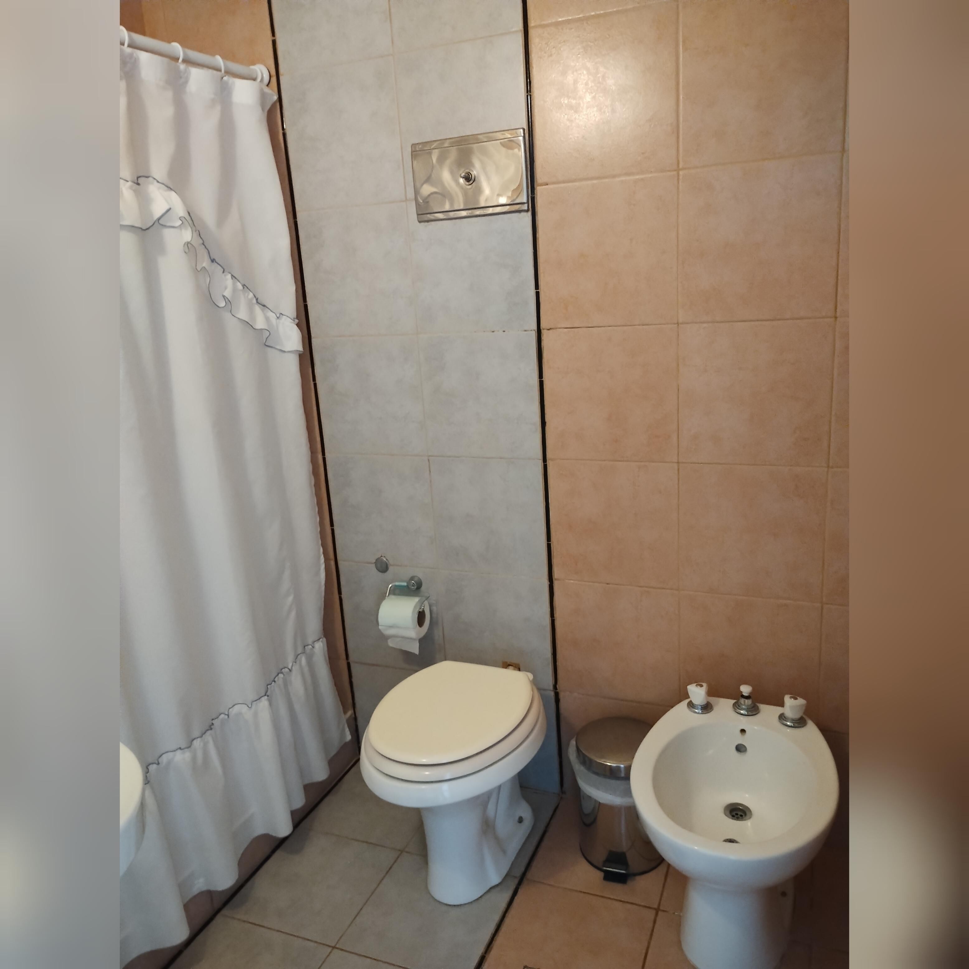 A bathroom with a toilet, bidet, and a shower curtain.