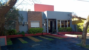 A building with a brick facade, a large glass entrance, and a paved driveway. - La Posada de Los Fresnos (Colon)