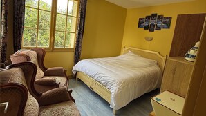 A bedroom with a bed, a wooden wardrobe, a chair, and a window with curtains. - ☀️ Apartment in a quiet residence located 20 m from the beach ☀️ (Houlgate)