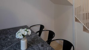 A modern interior with a marble dining table, a white vase with flowers, and a hanging light fixture. - MOT Teatro Soho (Buenos Aires)