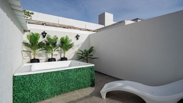 A modern outdoor bathroom with a white sink, green wall, and a white bench. - MOT Teatro Soho (Buenos Aires)