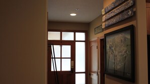 A hallway with wooden doors, a framed map on the wall, and directional signs above the doors.