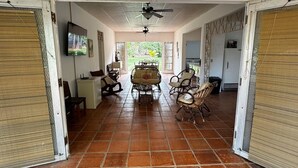 A spacious room with a tiled floor, a dining area with chairs and a table, a ceiling fan, and a TV on the wall. - 3-bedroom house in terrific Coronado Beach with WiFi, AC, BBQ area (Las Lajas)