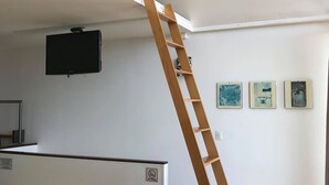 A room with a wooden ladder, a mounted TV, and artwork on the wall. - HOTEL Y AUTO HOTEL SECRETO (Mineral del Monte)