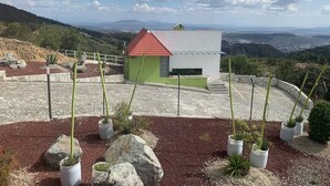 A small building with a red roof and a white exterior, surrounded by a landscaped area with potted plants and rocks. - HOTEL Y AUTO HOTEL SECRETO (Mineral del Monte)