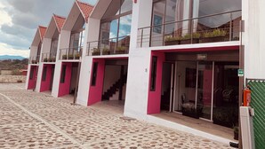 A row of modern buildings with large windows and balconies, featuring a mix of red and white colors. - HOTEL Y AUTO HOTEL SECRETO (Mineral del Monte)