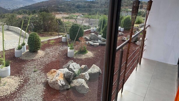 A landscaped outdoor area with potted plants, rocks, and a view of distant hills. - HOTEL Y AUTO HOTEL SECRETO (Mineral del Monte)