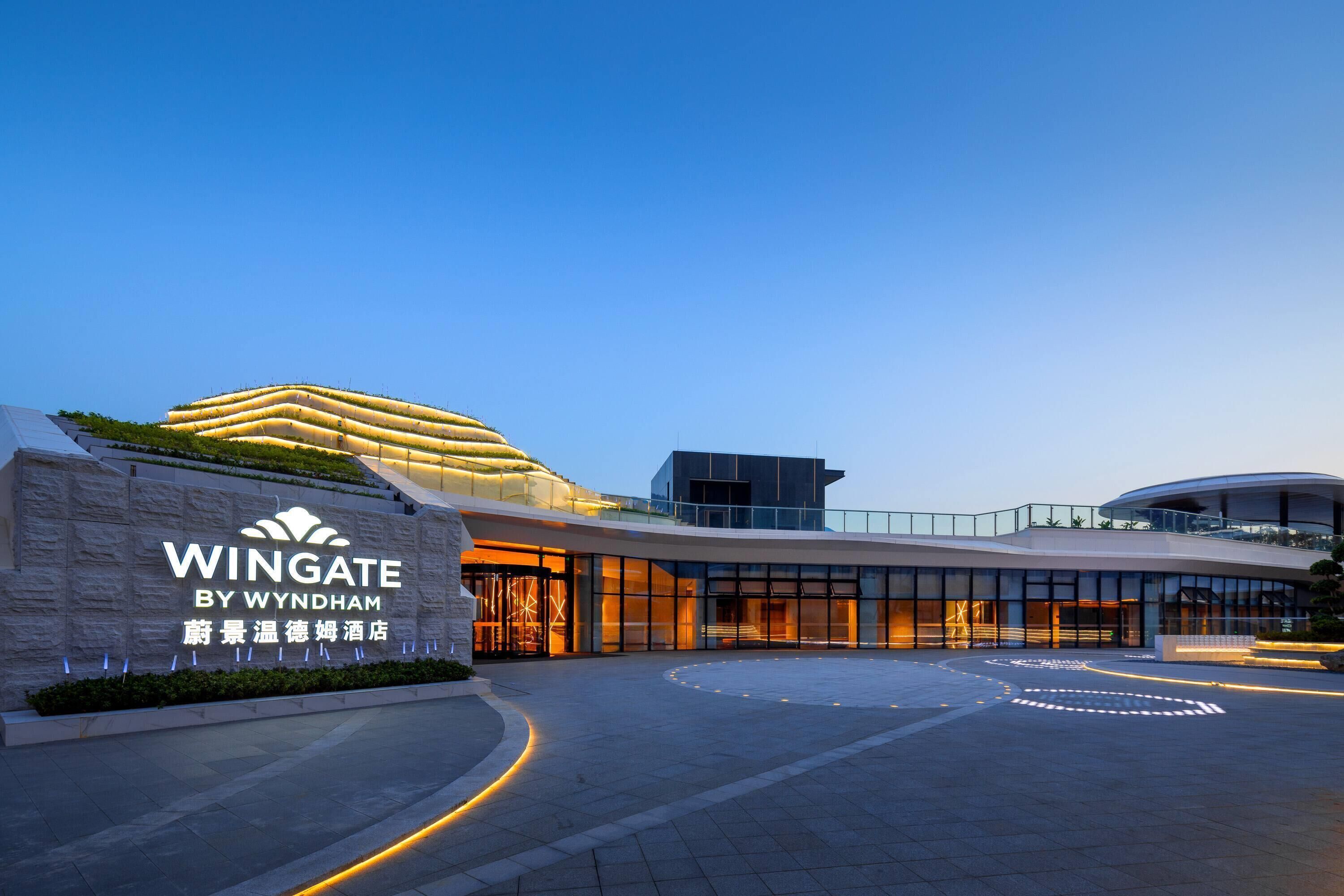 A modern hotel entrance with a curved driveway and illuminated signage.