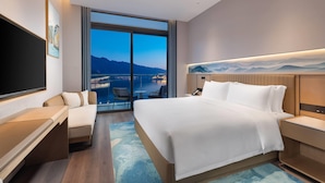 A modern hotel room with a large bed, a desk, a chair, and a TV.