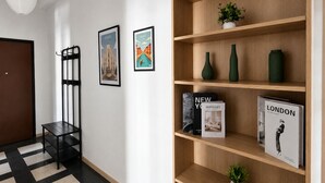 A hallway with a black and white checkered floor, a wooden bookshelf with books and decorative items, and two framed pictures on the wall.