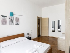 Ein Hotelzimmer mit Bett, Nachttisch, Lampe und Kleiderschrank.