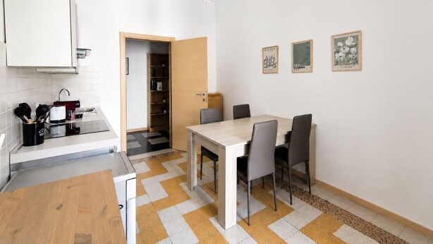 A modern kitchen with a dining area, a wooden table, and chairs.