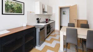 A modern kitchen with white cabinets, a stainless steel stove, and a dining area with a wooden table and chairs.