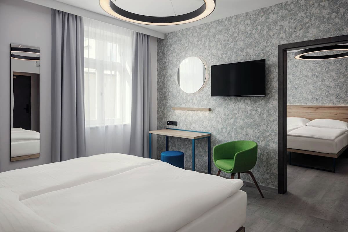 Une chambre d’hôtel moderne équipée d’un grand lit, d’un bureau avec une chaise, d’une télévision et d’un miroir.