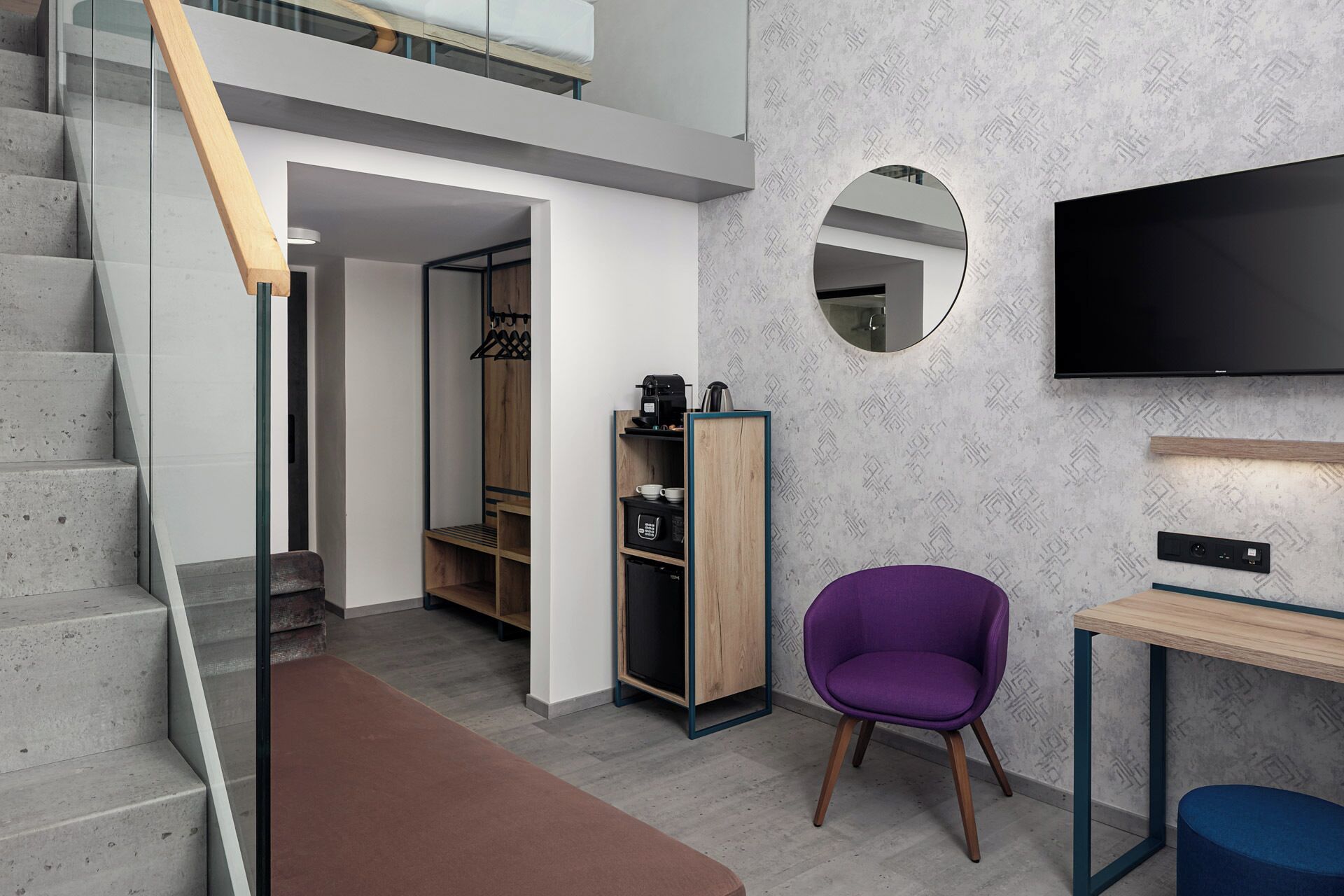 A modern interior with a staircase, a wardrobe, a purple chair, a table, and a TV mounted on the wall.