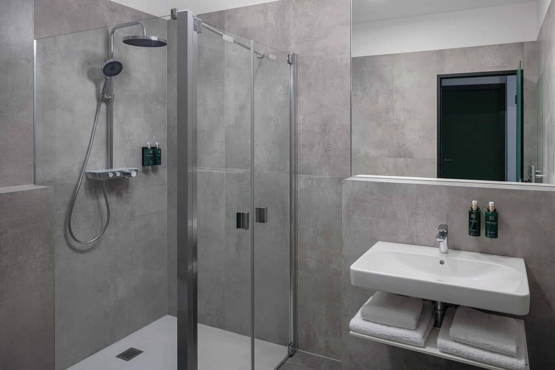 Une salle de bain moderne avec une douche à parois de verre, un lavabo blanc et un miroir au-dessus.