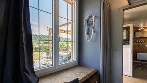 Una habitación con un ventanal grande, un banco de madera y vistas a un jardín con mobiliario exterior.
