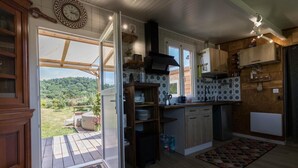 Una cocina con vistas a un jardín, armarios de madera, estufa integrada y un amplio ventanal.
