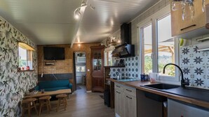 Una cocina compacta con armarios de madera, horno empotrado y ventana con vistas a un jardín.
