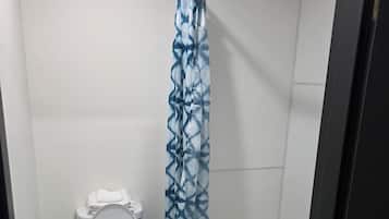 A small bathroom with a toilet, a shower curtain, and a bathtub.