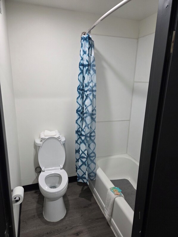 Une petite salle de bain avec des toilettes, un rideau de douche et une baignoire.