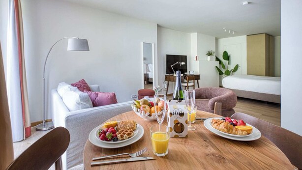 Ein Essbereich mit einem Holztisch, gedeckt für ein Frühstück, inklusive Waffeln, Obst und Saft.