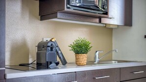 Eine Küche mit Kaffeemaschine, einer Topfpflanze, einer Mikrowelle und einem Spülbecken.