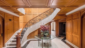 Una imponente escalera con una mesa de cristal y un arreglo floral en la parte inferior.