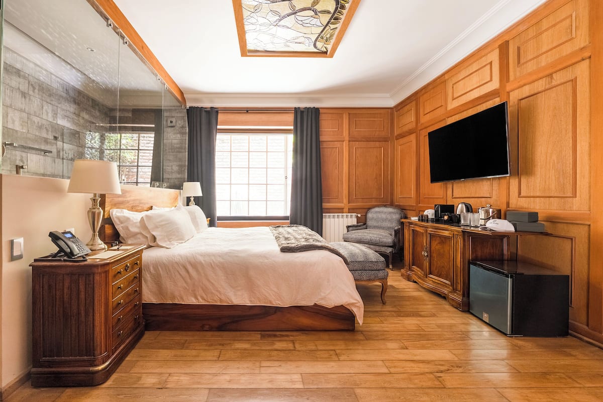 Une chambre d’hôtel avec un grand lit, un bureau doté d’un téléviseur à écran plat, un petit réfrigérateur et une fenêtre avec des rideaux.