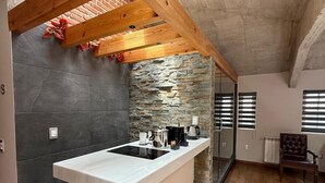 Una cocina moderna con una isla central, pared de piedra y vigas de madera.