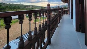 Un balcon avec vue sur une rivière et des collines.