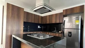 Une cuisine moderne dotée d’un îlot central, d’appareils électroménagers en acier inoxydable et de meubles de rangement en bois.