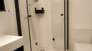 A modern bathroom with a glass-enclosed shower, a white toilet, and a vanity with a black countertop.