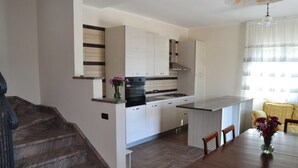A modern kitchen with white cabinets, a black stove, and a wooden staircase. - Sorrento room, room with private bathroom, 20 Min from Pompeii, 40 from Sorrento and Amalfi (Campania)