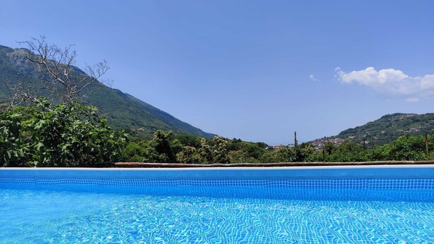 A clear blue pool with a tiled bottom, surrounded by lush greenery and hills in the background. - Sorrento room, room with private bathroom, 20 Min from Pompeii, 40 from Sorrento and Amalfi (Campania)