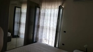 A bedroom with a bed, a wardrobe, a mirror, and a window with curtains. - Sorrento room, room with private bathroom, 20 Min from Pompeii, 40 from Sorrento and Amalfi (Campania)
