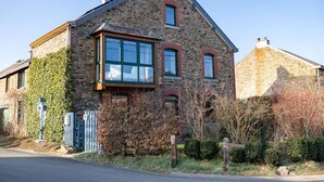 A stone house with a gabled roof, large windows, and a small attached garage. - Maison la Gileppe (Jalhay)