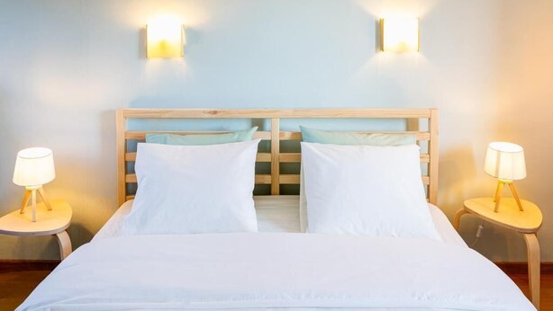 A double bed with white linens, two bedside lamps, and a wooden headboard. - Maison la Gileppe (Jalhay)
