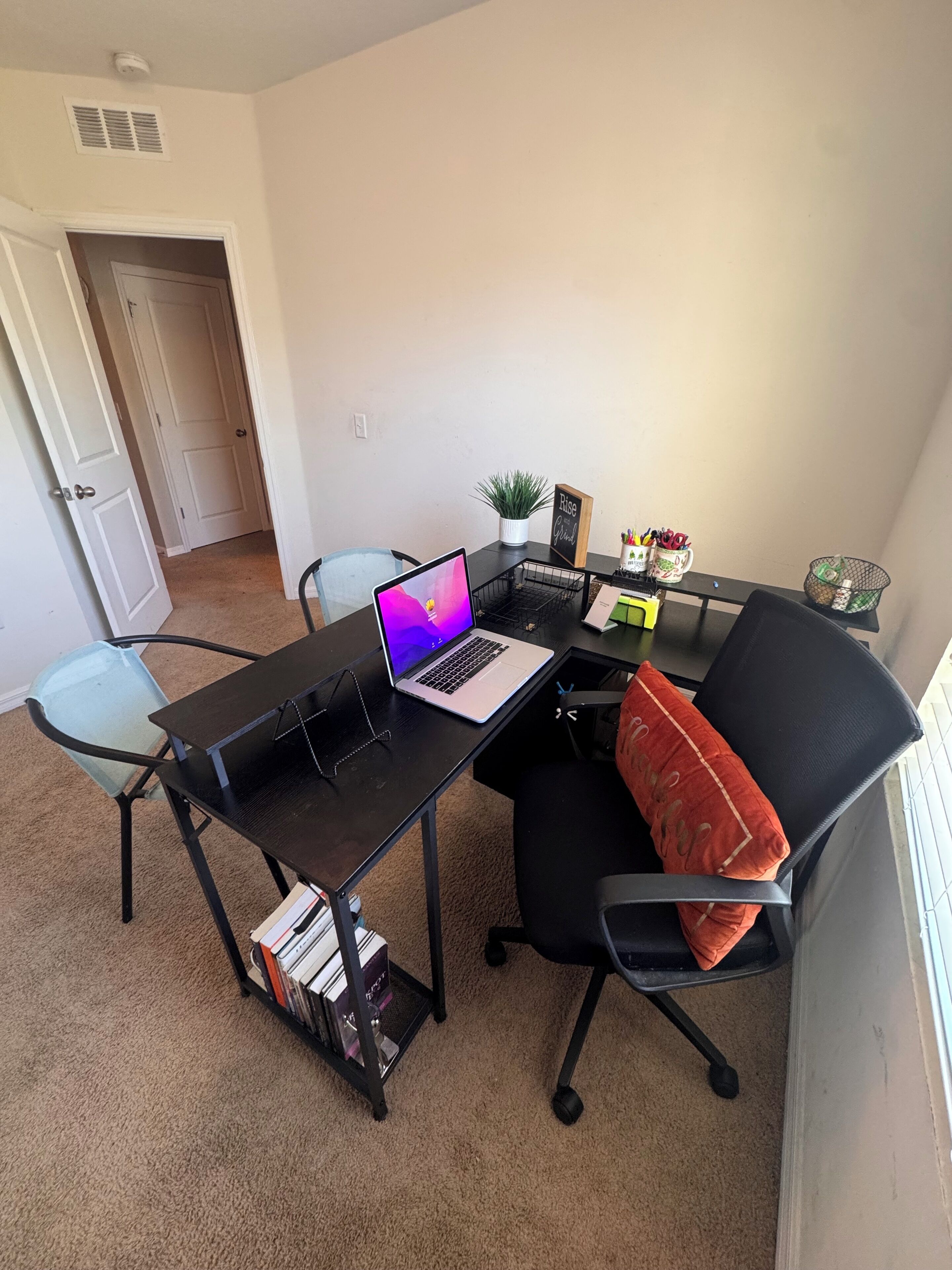 Un petit bureau comprenant un bureau, un ordinateur portable, une chaise et quelques objets décoratifs.