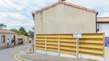 Un edificio con facciata beige e tetto a tegole, una recinzione gialla e una strada con pedoni.