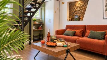 A modern living room with a wooden staircase, a sofa set, a coffee table with snacks, and a decorative wall.