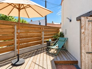 Eine Holzterrasse mit Tisch, Stühlen und Sonnenschirm, sowie ein Holzzaun.
