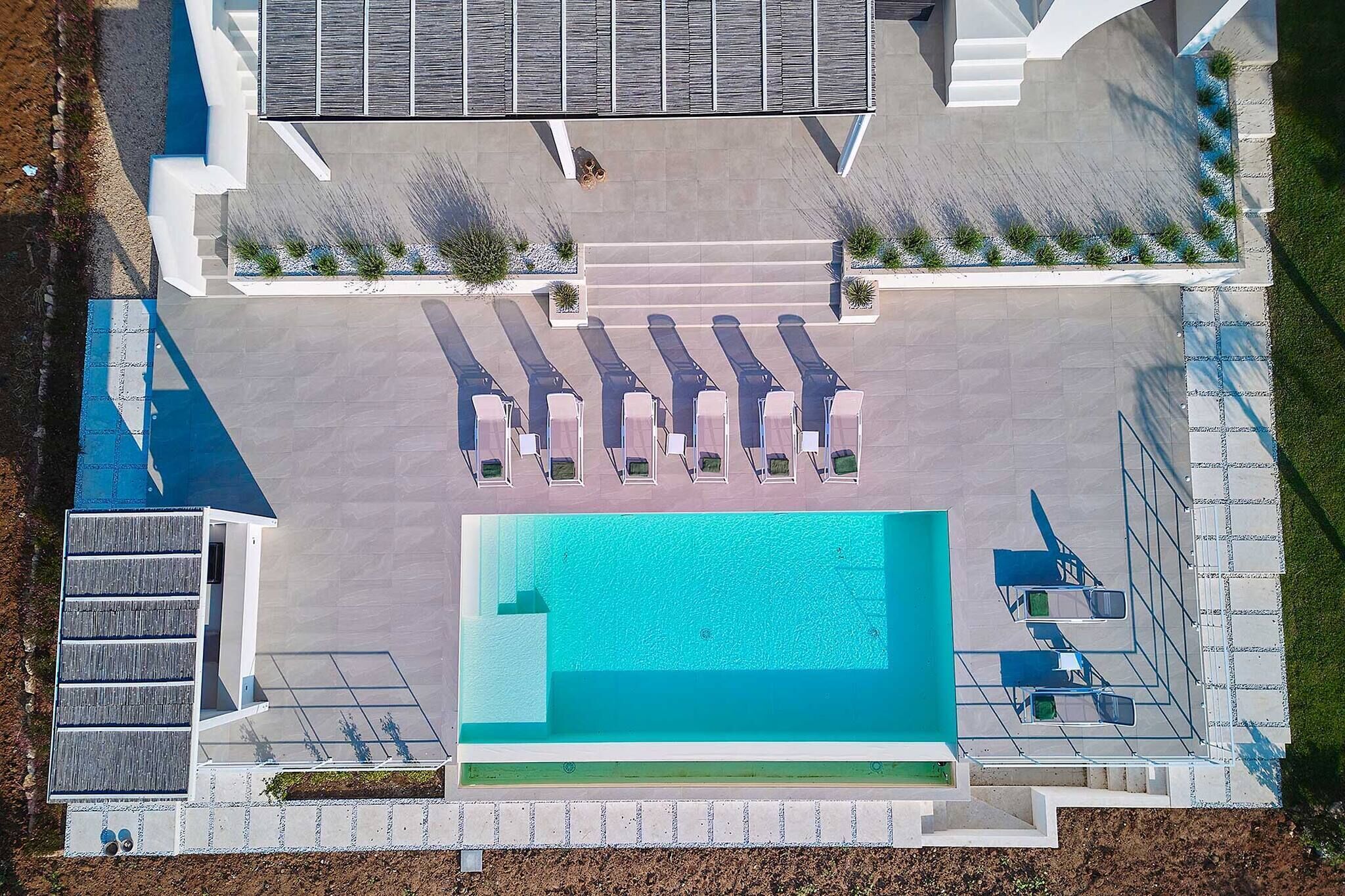 Ein Luftbild eines Poolbereichs mit Liegestühlen und einem kleinen Gebäudebau.