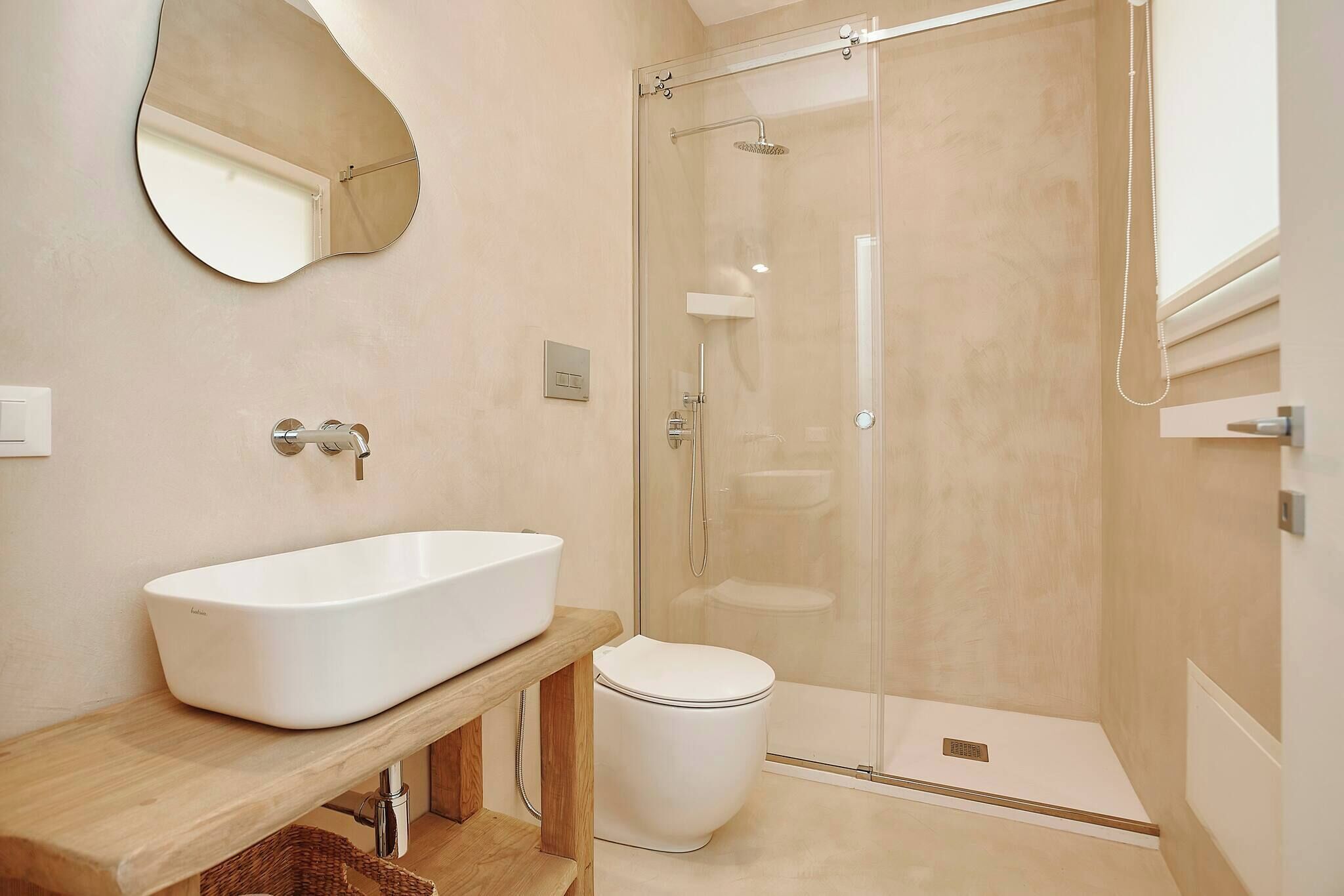 A modern bathroom with a freestanding sink, a toilet, and a glass-enclosed shower.