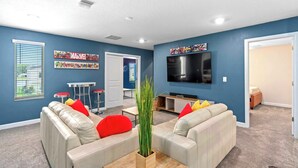 A living room with two sofas, a coffee table, a TV, and a bar area with stools.
