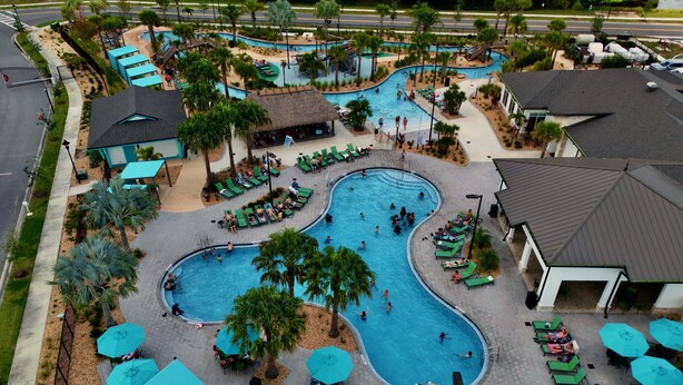 A large outdoor swimming pool with multiple lanes, surrounded by lounge chairs and umbrellas.