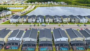 A residential area with multiple houses, a large pond, and a parking lot.