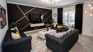 A modern living room with a black and white color scheme, featuring a sofa set, a coffee table, and a flat-screen TV mounted on the wall.