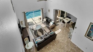 A spacious living area with a pool, a ceiling fan, and a view of the outdoors. - Lakeview Retreat with Private Pool & Games (Kissimmee)