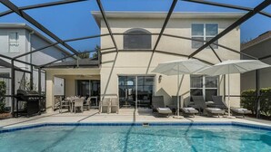 A swimming pool with a covered patio area, lounge chairs, and a grill. - Lakeview Retreat with Private Pool & Games (Kissimmee)